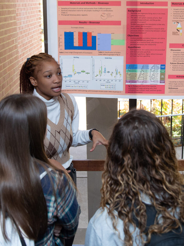 A student presenting her Epic Expo research in front of her poster to two girls. 