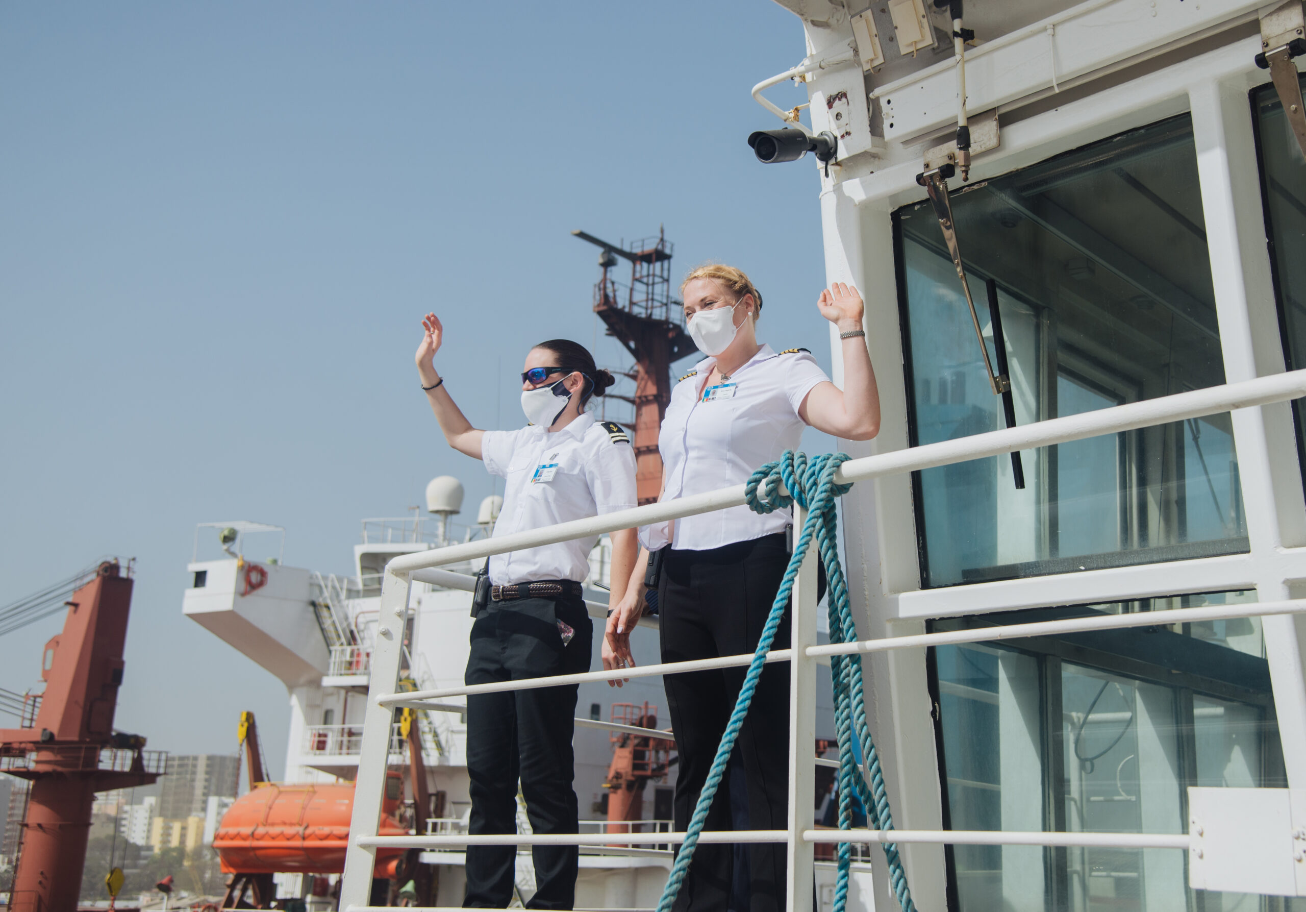 Alexandra Hagerty ’07(right) and Chief MateEmily Bull wave to the crowd after dockingthe MercyShips vesselin Africa.      