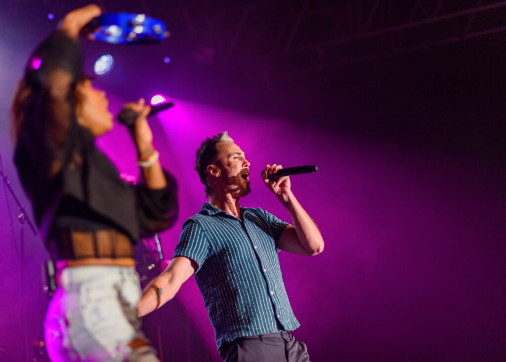 Fitz and the Tantrums performing under purple stage lights. 
