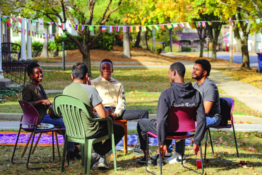Students sit in lawn chairs together enjoying a campus gathering. 