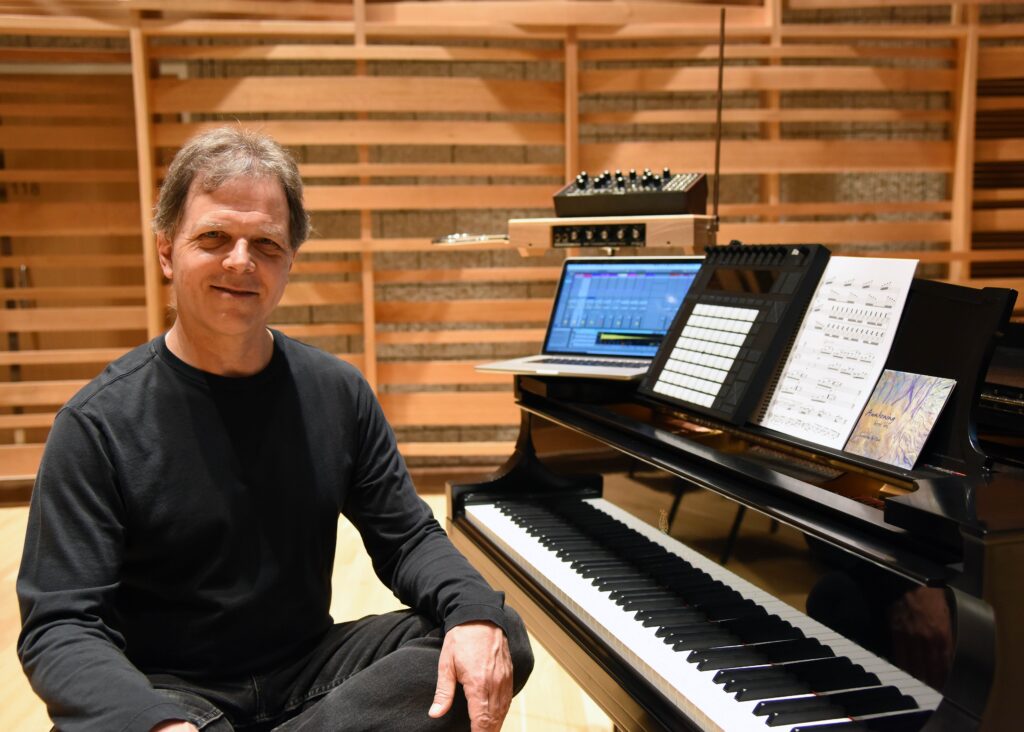 Faculty member Forrest Tobey sits at a piano