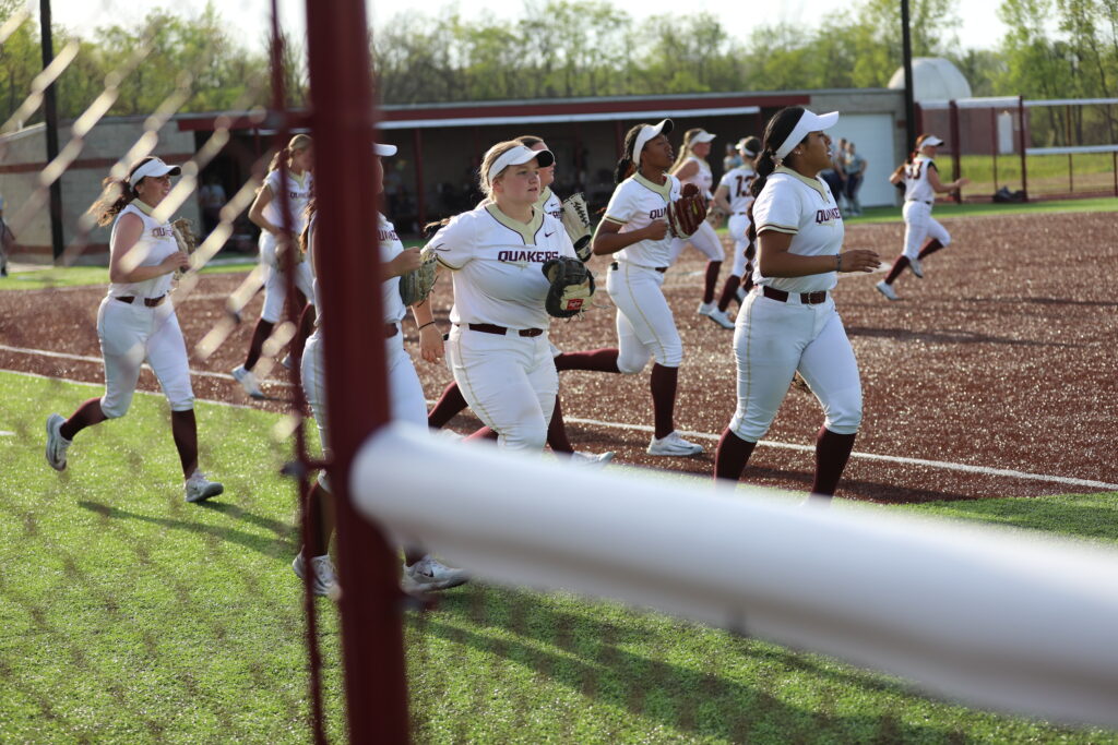 Earlham College softball players rush on to the field during a game in spring 2024.